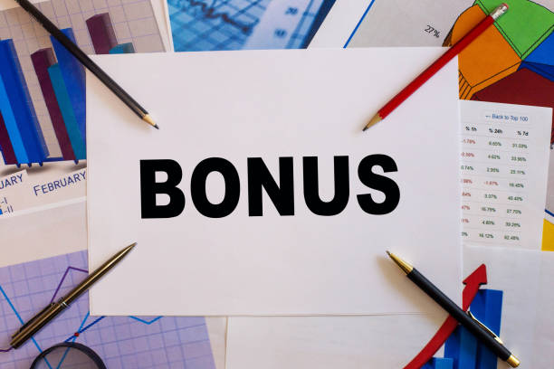 słowo bonus napisane na białej kartce papieru na tle wykresów obok ołówków - performance perks incentive coin zdjęcia i obrazy z banku zdjęć