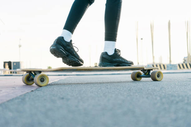 istock Unrecognizable woman rides on longboard around sunlit park. 1223842425
