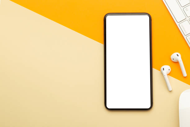 istock Flat lay, top view of orange office table desk with smartphone blank screen mockup with clipping path and wireless earphones, keyboard, mouse. Modern working space 1223843546