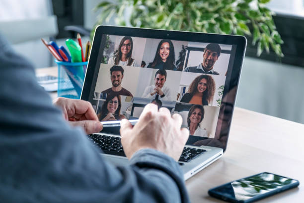 male employee speaking on video call with diverse colleagues on online briefing with laptop at home. - business conference meeting teamwork imagens e fotografias de stock