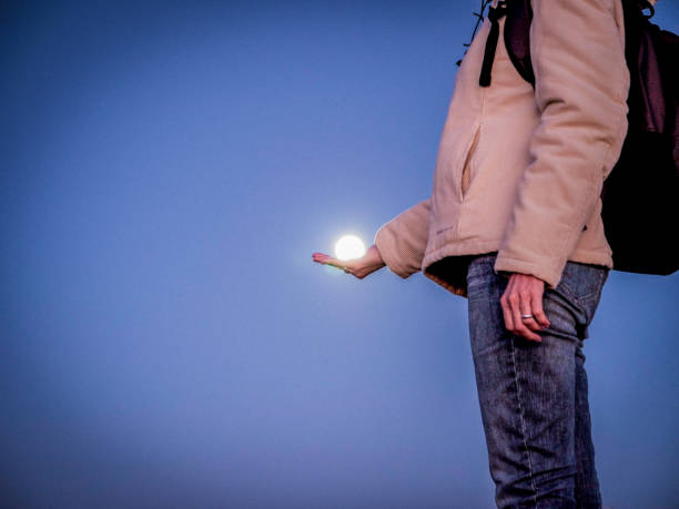 A female hiker holding the moon on her hands, optical illusion