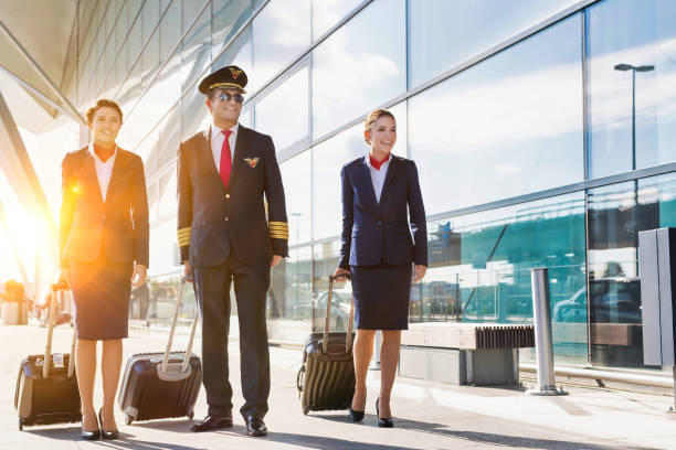 空港を歩く若い美しい客室乗務員と成熟したパイロット - cabin crew pilot airport walking ストックフォトと画像