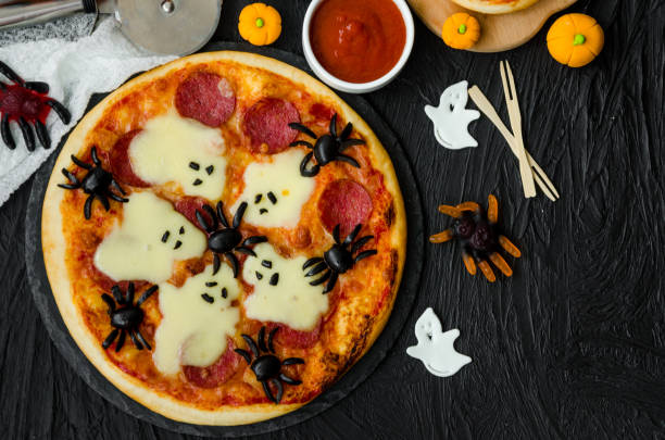 istock Halloween Pizza Monsters with cheese Ghost and olive Spider on a black background. Food idea for Halloween party. 1223860003