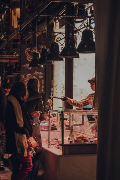 mujer probando comida de un puesto en mercado de san miguel, madrid, españa. - kiosk editorial traditional culture famous place fotografías e imágenes de stock