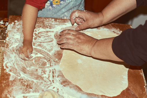 Family concept. Cooking together with children. Little girl leaning how to make manti dumplings. Close up child and grandmother hands