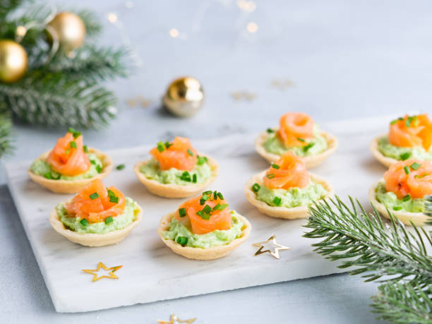 크리스마스 장식과 밝은 배경에 연어 아보카도 크림 치즈와 휴일 전채 카나페. 새해와 크리스마스 휴일을위한 축제 테이블 조리법 아이디어. - canape appetizer gourmet salmon 뉴스 사진 이미지