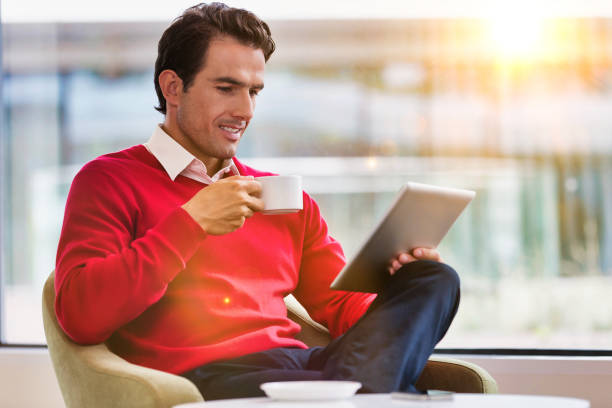 istock Portrait of attractive businessman using digital tablet while sitting and drinking coffee in lobby 1223864769