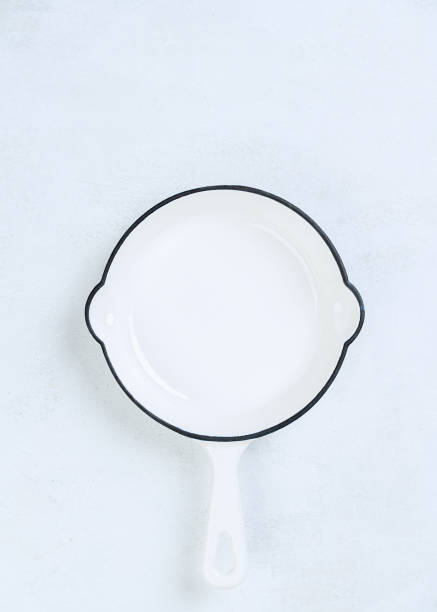istock White Empty cast iron frying pan on light culinary background, view from above. Free space for menu or recipes. Cooking food background. 1223865920