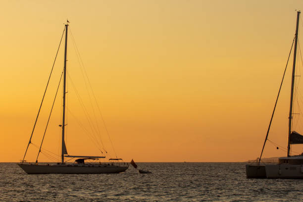 The sun sets over the Aegean Islands. A catamaran is in the background.