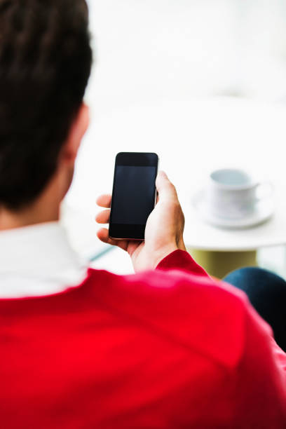 istock Businessman using smartphone while sitting and drinking coffee in lobby 1223868643