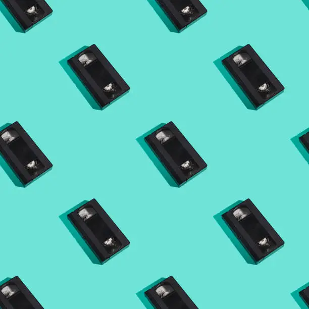 Photo of VHS format plastic videotape cassette seamless pattern, analog retro technology magnetic storage tape on minimal mint green background