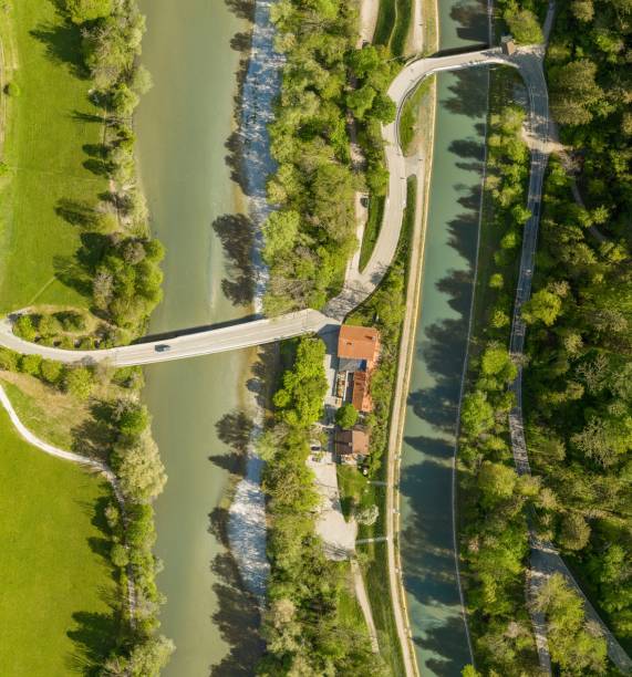 istock Top view from a drone at a driving car at a bridge over a river with a neaby forest and a house 1223873633
