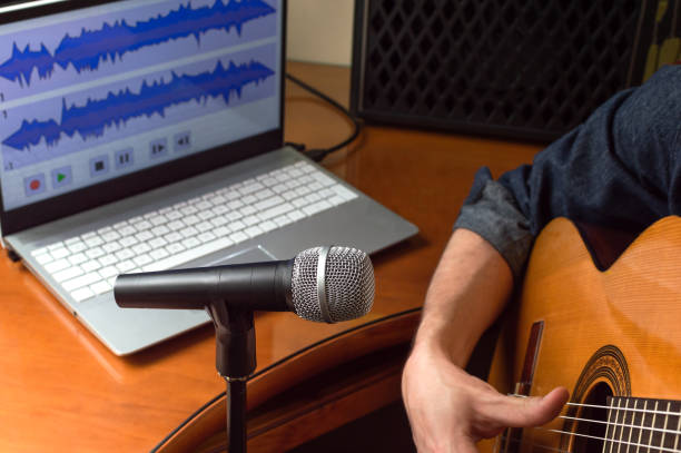 istock Person recording a song played on the guitar using microphone and computer. Young guitarist recording music at home. 1223874614