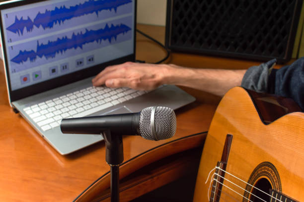 istock Person recording a song played on the guitar using microphone and computer. Young guitarist recording music at home. 1223874616