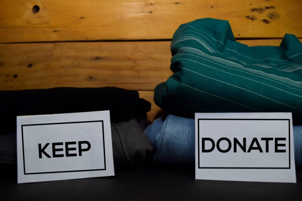 Keep and Donate write on a sticky note between fashion clothes folded and stack isolated on wooden background. Keep and Donate write on a sticky note between fashion clothes folded and stack isolated on wooden background. messy vs clean desk stock pictures, royalty-free photos & images