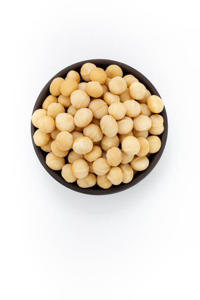 istock Cleaned Macadamia nuts in round bowl on white background, top view 1223877790