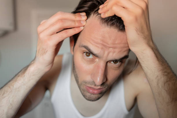 istock Young man looking at his hair in bathroom mirror 1223880816