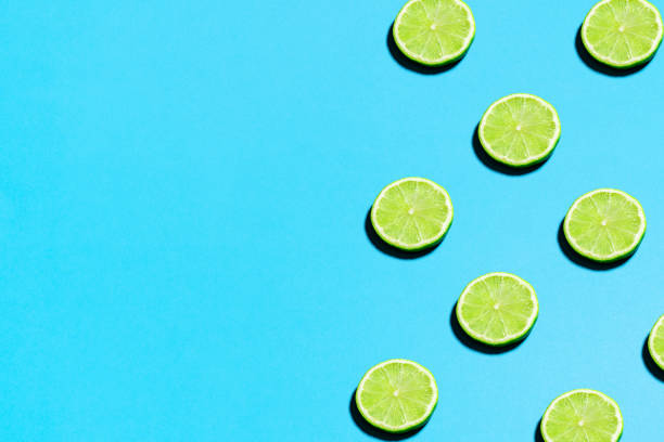istock Summer abstract trendy fresh concept. Lime pattern on bright light blue background, copy space. Minimal flat lay food texture 1223884031