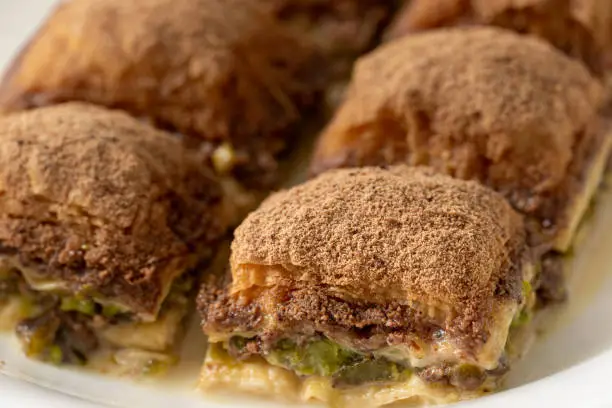 Photo of Turkish close up baklava with cocoa and milk on white plate