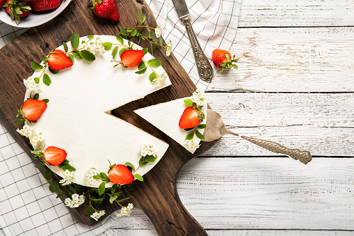 Homemade cheesecake decorated with strawberries on a wooden background