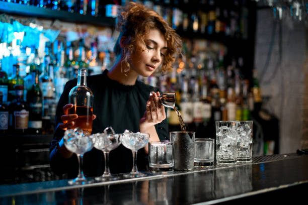 młoda barman pani ostrożnie wlewa napój do metalowego szkła za pomocą jiggera - spring cleaning women cleaning dancing zdjęcia i obrazy z banku zdjęć