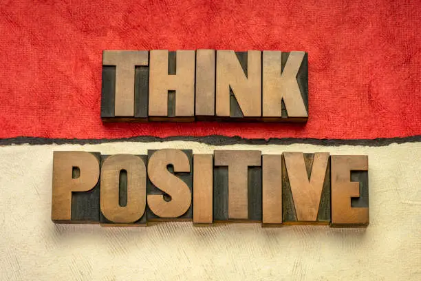 Think positive - word abstract in vintage letterpress wood type blocks against abstract paper landscape, optimism, positivity and mindset concept