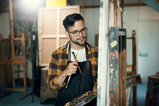 Young painter holding a color palette in his art studio