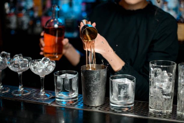 istock Close-up barman masterfully pours drink into metal glass using jigger 1223889075
