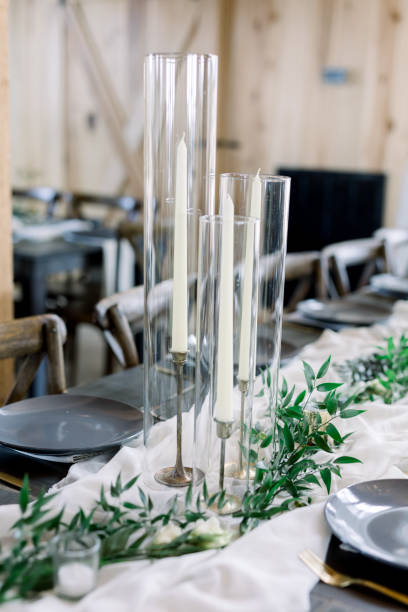 istock Cylinder Candle Holders with Tall Taper Candles Decorate a Table at a Wedding Reception, Decorated with Olive Leaves on Loose Tablecloth Cheesecloth Runner. 1223898639