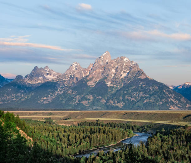 Snake River and the Teton Range at First Light The Snake River Overlook is the spot where Ansel Adams took his iconic photograph of the Snake River winding its way below the Teton Range. The scene pictured here was photographed just after sunrise, capturing the glow on the mountains. The Snake River Overlook is nine miles north of Moose Junction in Grand Teton National Park near Jackson, Wyoming, USA. jeff goulden grand teton national park stock pictures, royalty-free photos & images