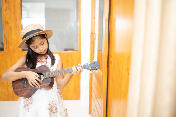 istock A cute Asian elementary school girl is playing the ukulele 1223904646
