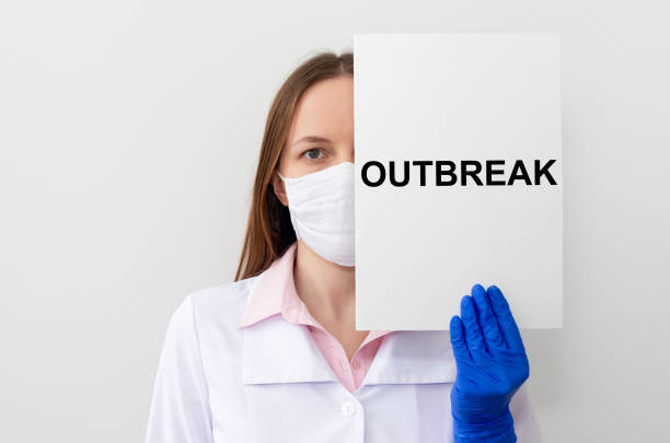 istock the word outbreak on a white paper in hands in protective gloves with doctors 1223905316