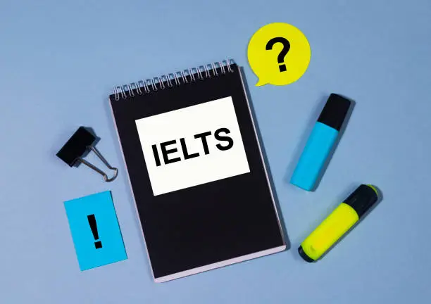 Test of English IELTS on notebook with markers and stickers. Top view, flatlay