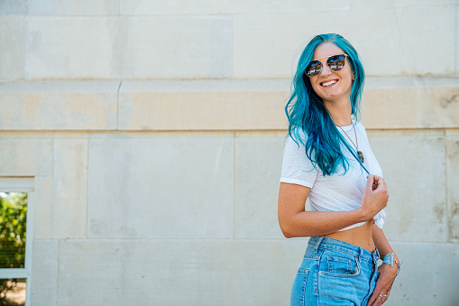 Unique Spunky Fashionable Young Woman with Fun Cute Teal Blue Green Dyed Hair Standing Outdoors in the Summer with Copy Space