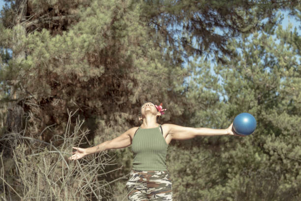Mature Woman doing pilates exercises outside in the middle of forest.