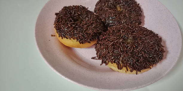 istock Donuts with chocolate sprinkles on a plate isolated on white background 1223910999