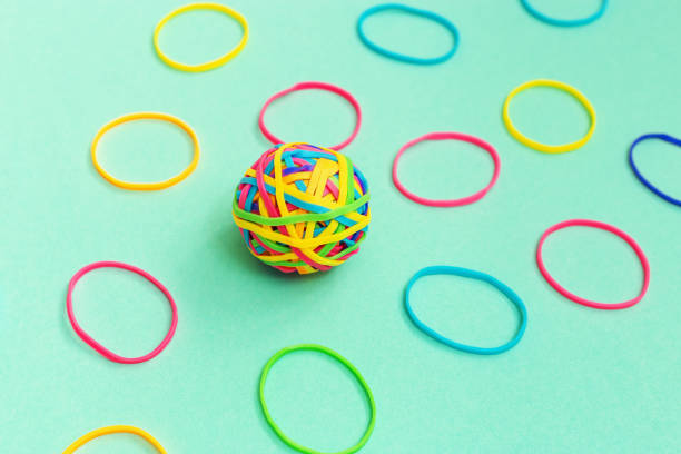 palla o nodo di sottili gomme elastiche multicolori su sfondo semplice. groviglio di pensieri. - flexibility rubber rubber band tangled foto e immagini stock