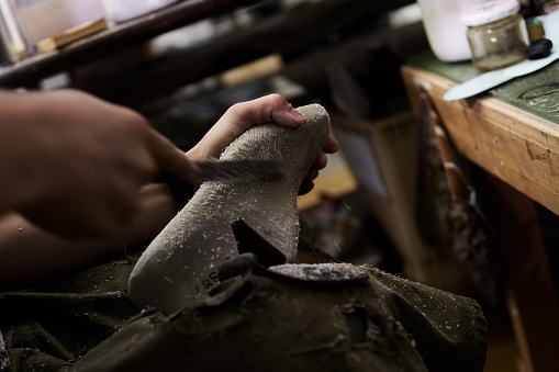 A shoemaker shaves a mold of a shoe in his workshop