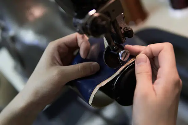 A woman's hand sewing leather with a sewing machine
