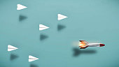 Paper plane race against a rocket missle . Powerful mindset and leadership concept . This is a 3d render illustration .