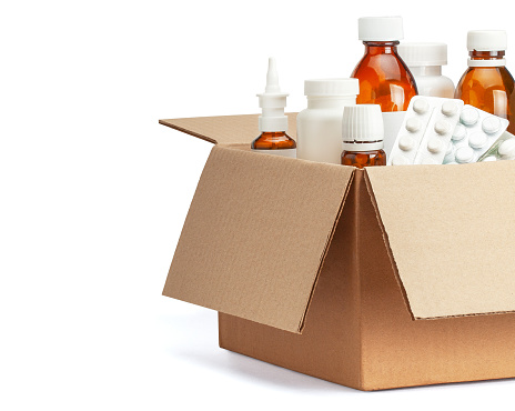 Delivery of medicines home from the pharmacy. Cardboard box with medicines, pills, bottles, sprays. Isolated on a white background.