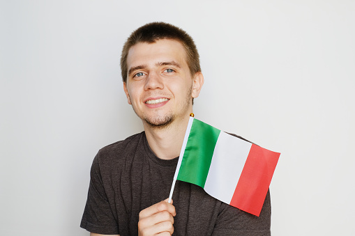 Man holding small italian flag, grey background