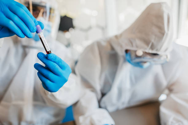 médicos em trajes de proteção com amostras de sangue - genetic research men chemical protective glove - fotografias e filmes do acervo
