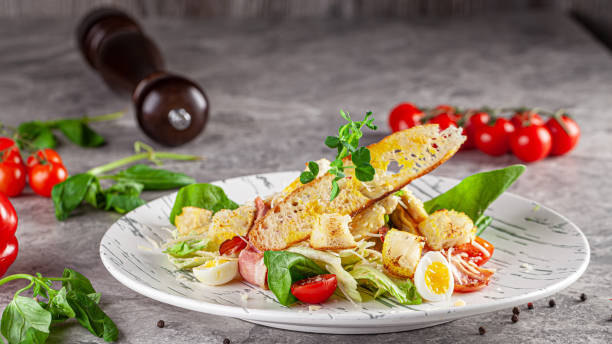 istock Italian Cuisine. Caesar salad with chicken, bacon, quail eggs, bread croutons, cherry tomatoes. Dish in a restaurant on a white plate. background image, copy space text 1223925436