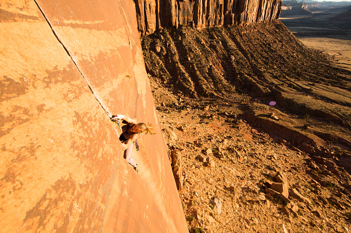 Strong young woman rock climbing in Utah on a beautiful fall day