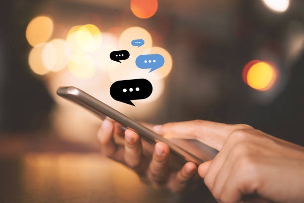 istock Woman hand using smart phone with chat icon graphic at coffee shop abstract background. 1223929565