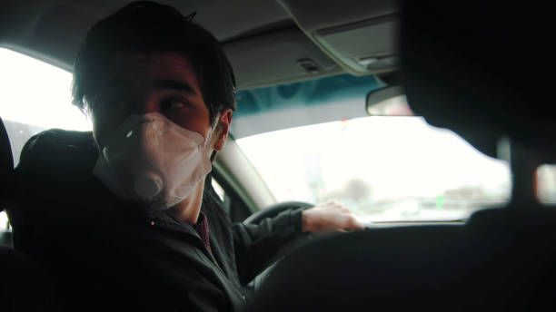 istock Young man inexperienced driver in protective mask driving a car and looking back 1223930489