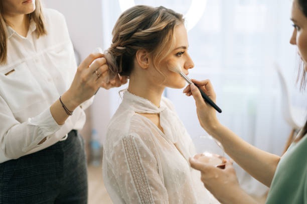istock Side view of make-up artist putting rouge on woman's cheek using brush 1223932482