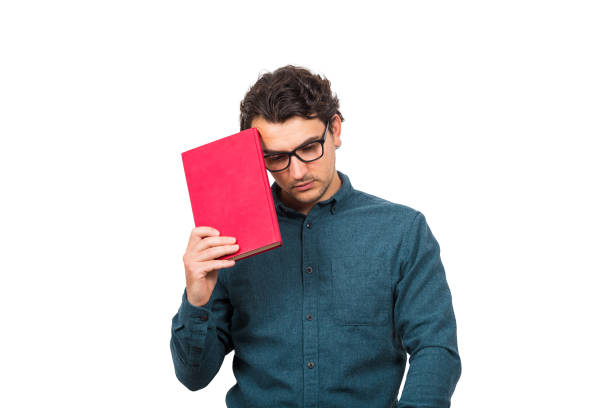 istock Pessimistic student guy looking down upset, as holds a book isolated on white background. Confused young man has learning troubles, negative face expression, study problems, education concept. 1223935377