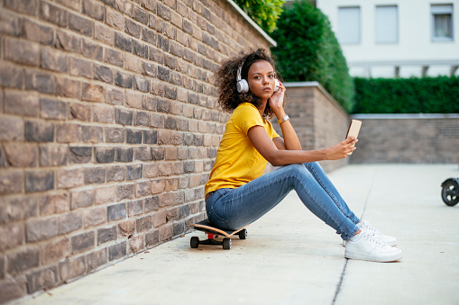 Skater girl with headphones using phone
